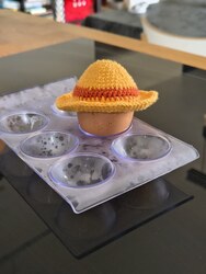 Un œuf coiffé d'un chapeau de paille jaune au crochet avec un ruban rouge, façon One Piece