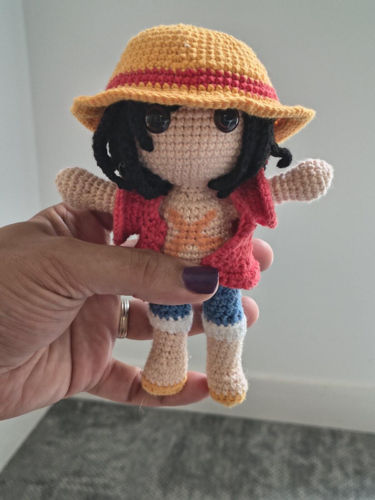 Travail en cours : l'amigurumi avec son gilet rouge et son chapeau de paille, avant l'ajout de la ceinture jaune