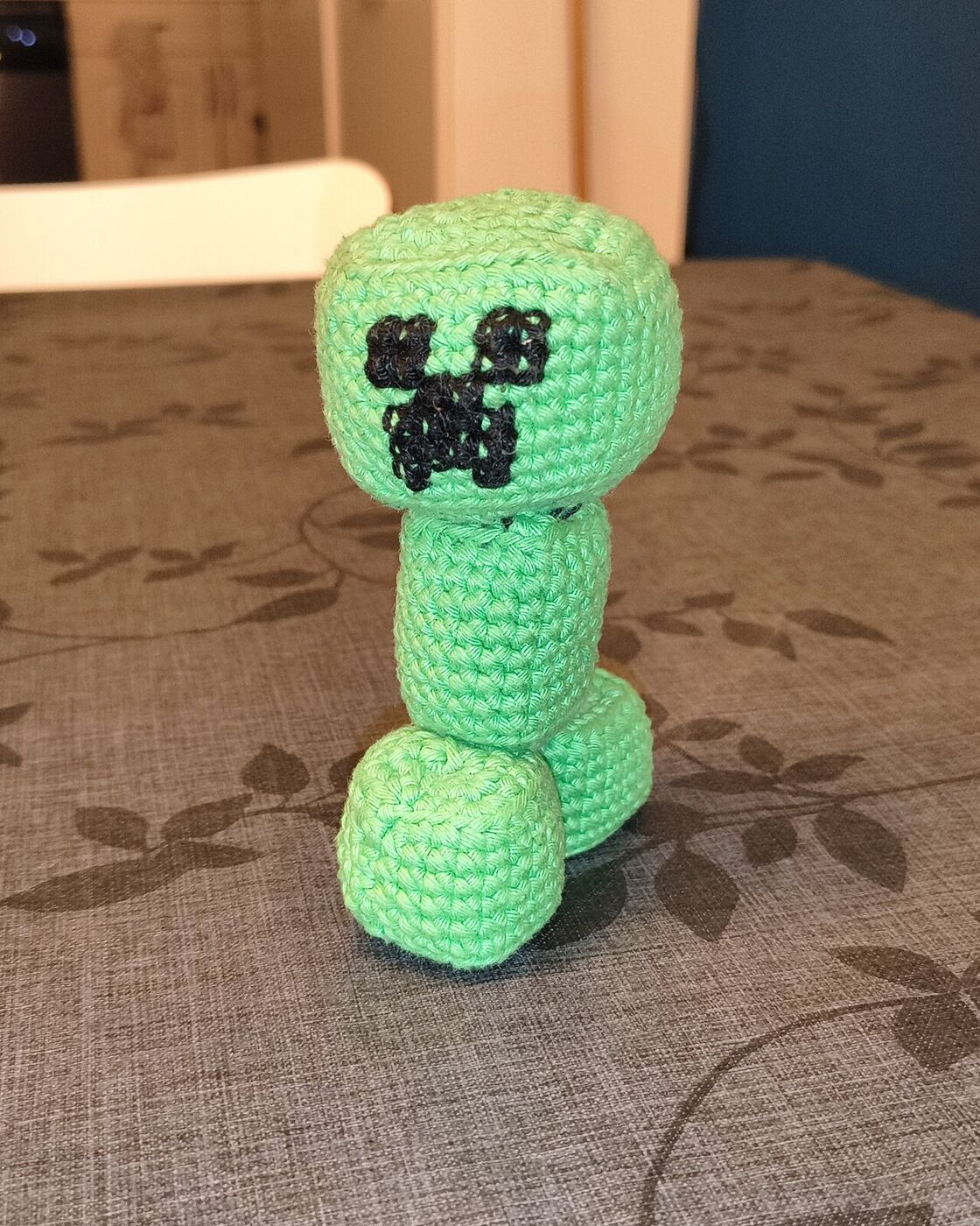 L'amigurumi Creeper de Minecraft terminé, debout sur la table de la cuisine, face à l'objectif